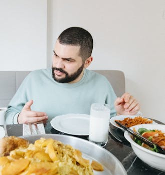 A bearded man in İstanbul dining on a Turkish meal with various dishes and milk.