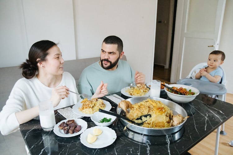 Family With A Little Baby Boy Eating Dinner At Home 