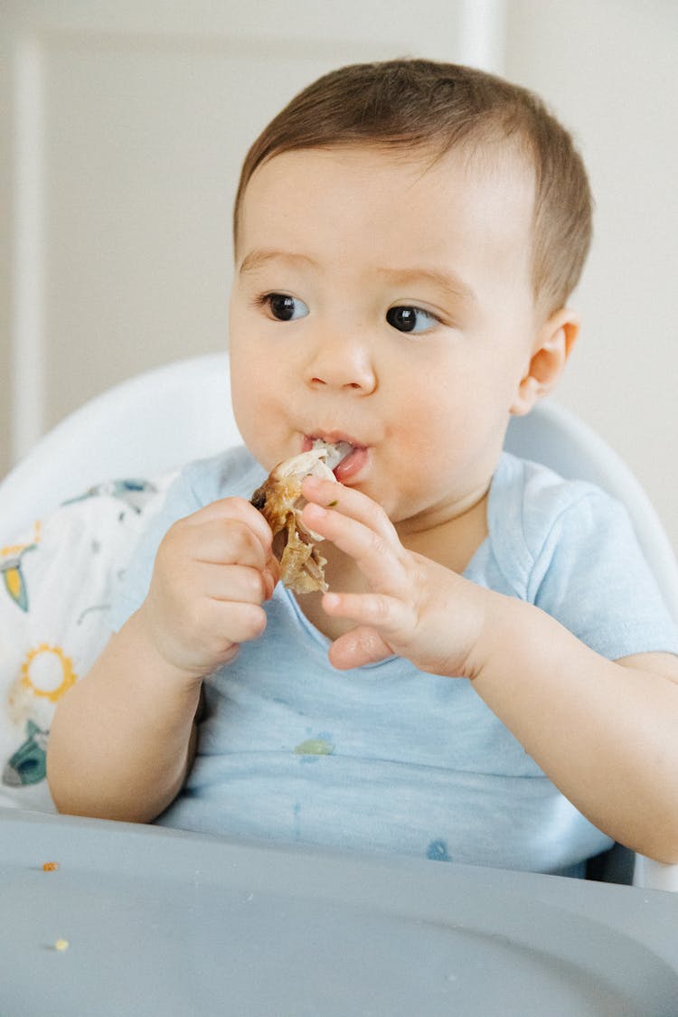 A Close-Up Shot Of An Infant Eating Food