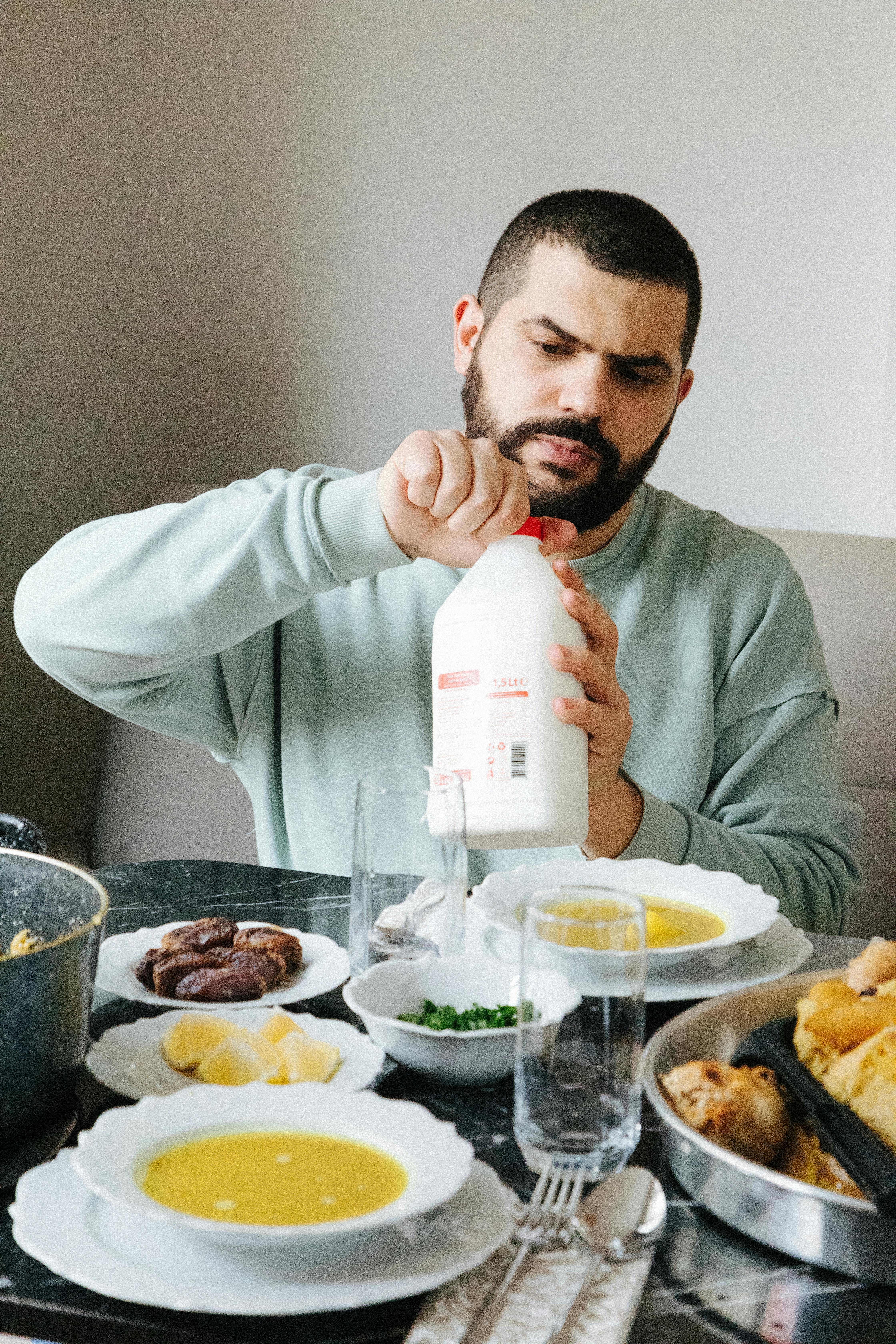 A man opening a milk bottle during a traditional Turkish breakfast in Istanbul, Turkey.