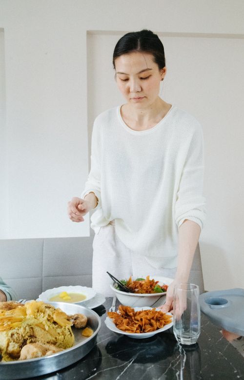 Free An adult woman sets a table with dishes in a bright dining room. Stock Photo