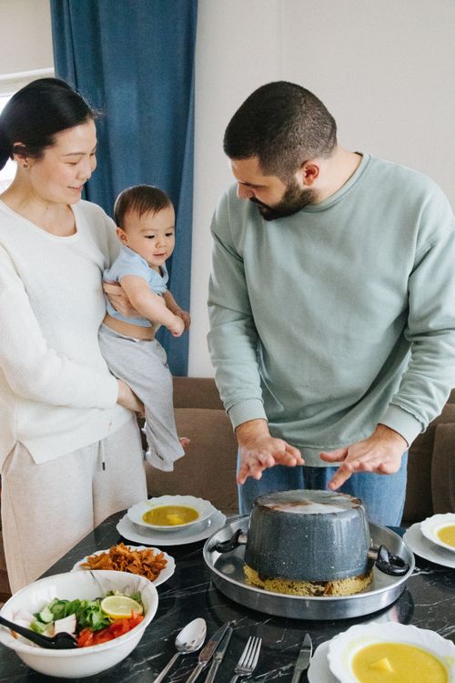 Free A young family gathers around a table sharing a meal with lively conversation. Stock Photo
