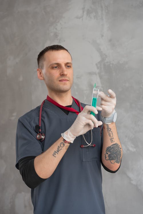 Man in Grey Scrub Suit Holding a Syringe