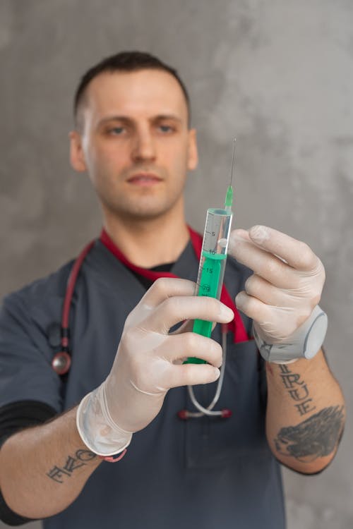 Man in Grey Scrub Suit Holding a Syringe