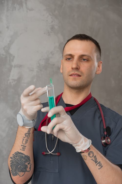 Man in Grey Scrub Suit Holding a Syringe