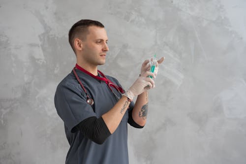 Man in Grey Scrub Suit Holding a Syringe