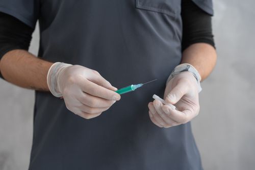 Free Close-up of a healthcare worker's hands holding a syringe for medical procedures. Stock Photo
