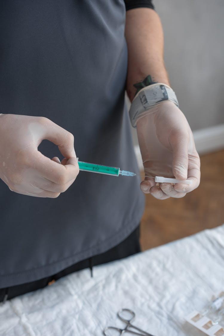 Person Using Gloves Holding A Syringe