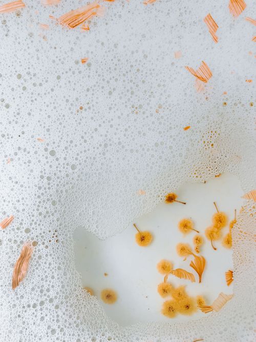 Free Top view of small colorful flowers on bottom of bathtub with foam and bubbles on clear water surface in bathroom Stock Photo