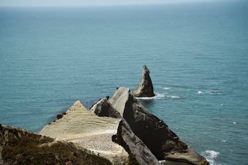 Rocky cliff in waving sea in daylight