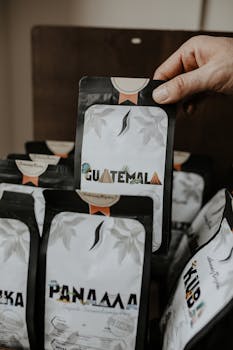 Close-up of a hand holding a Guatemala coffee package among other coffee bags.
