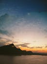Silhouette of a Mountain Near the Sea During Sunset