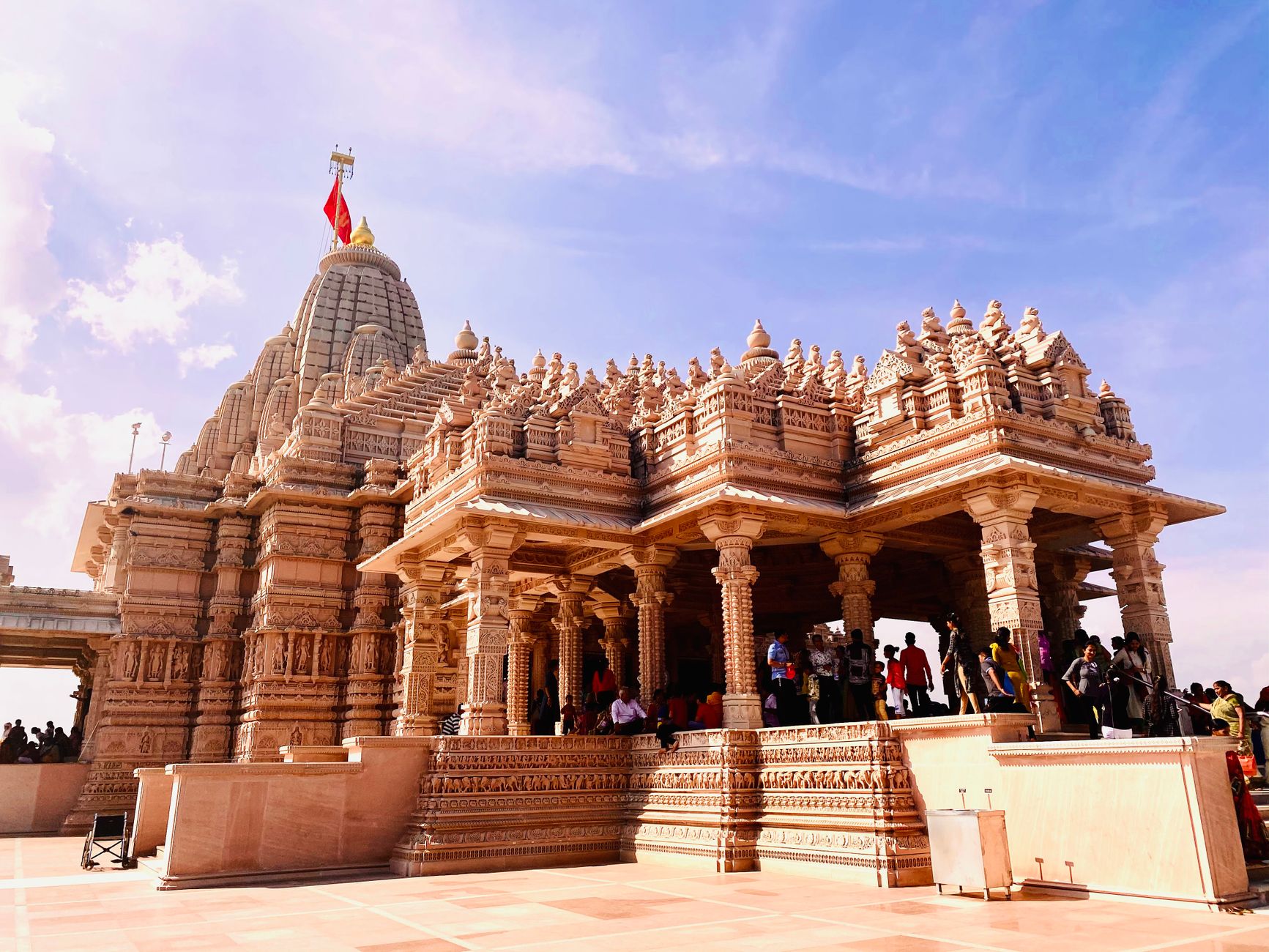 An impressive Hindu temple with detailed carvings and a vibrant flag under a clear blue sky.
