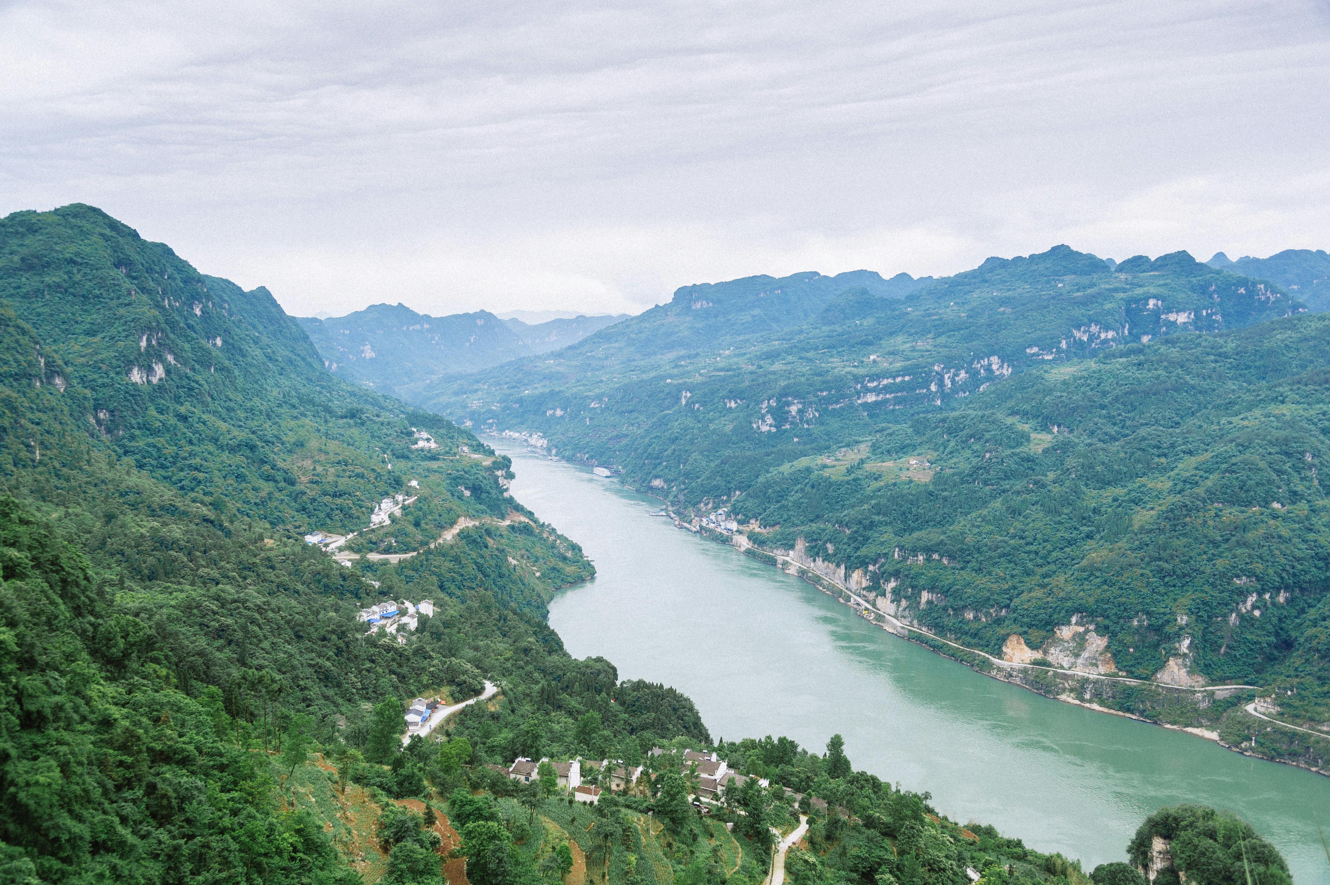 Luxury cruise ship navigating Yangtze River through Three Gorges at golden hour with misty limestone cliffs