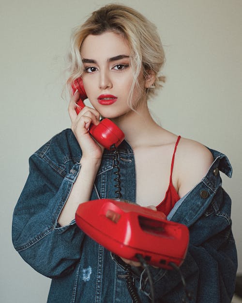 Photo of a Woman Using a Red Telephone