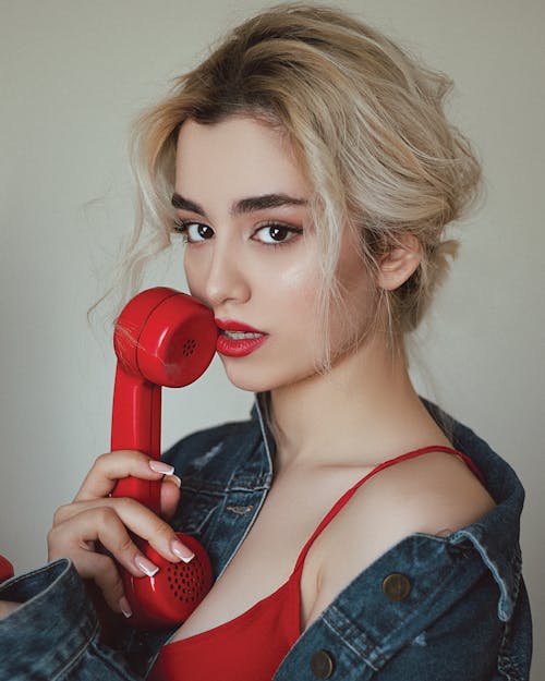 A Beautiful Holding a Red Telephone