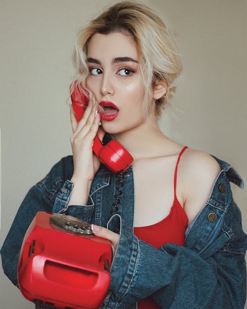 Woman in Denim Jacket Holding Red Telephone