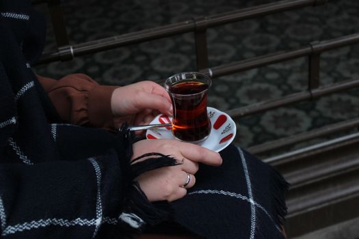 A Person's Hands Holding a Saucer with a Glass of Tea