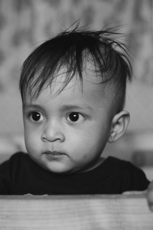 Free Captivating black and white close-up of a cute toddler with expressive eyes, showcasing innocence. Stock Photo