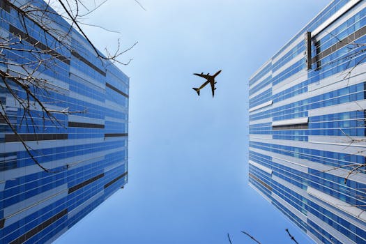 A striking low angle shot capturing skyscrapers and an airplane above a clear blue sky.