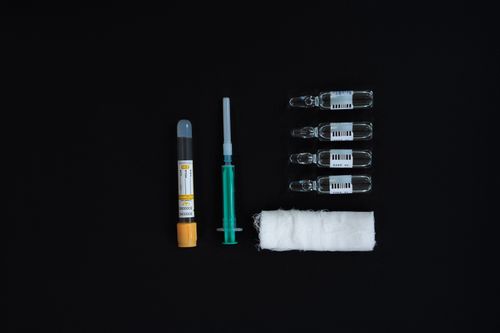 Free Flat lay of medical supplies including syringes, ampoules, and bandages on a black background. Stock Photo