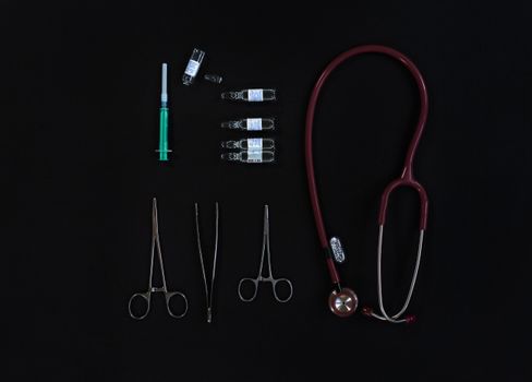 Flat lay of medical equipment including stethoscope, syringe, and tools.