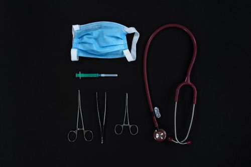 Free Top view of medical tools including a mask, syringe, and stethoscope on a black surface. Stock Photo