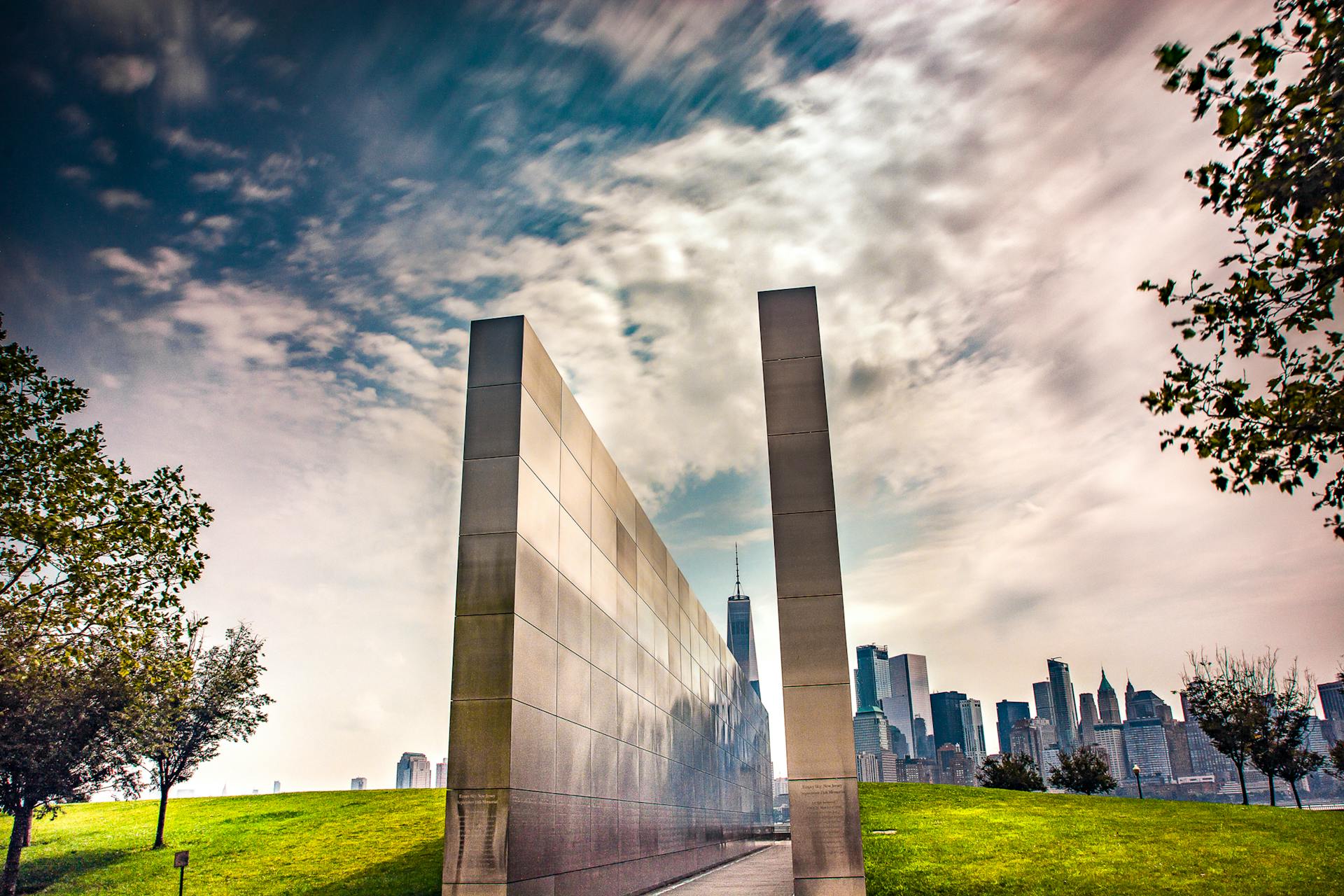 Stunning reflection memorial with New York City skyline in the background under a dynamic sky.