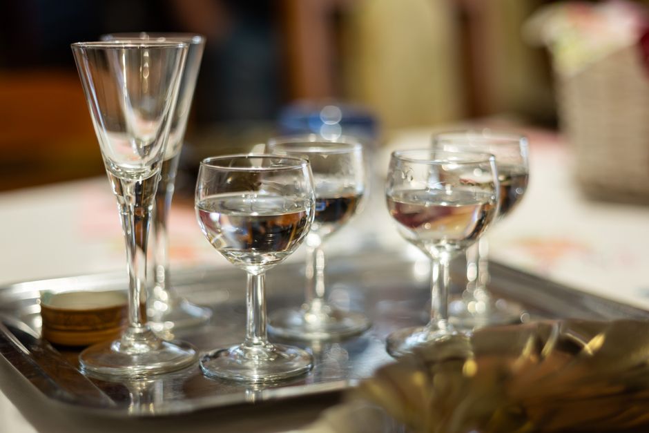 Close-up of wine glasses and shot glasses on a serving tray under soft indoor lighting.