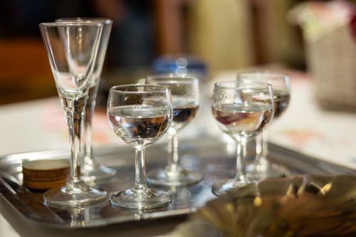 Free Close-up of wine glasses and shot glasses on a serving tray under soft indoor lighting. Stock Photo