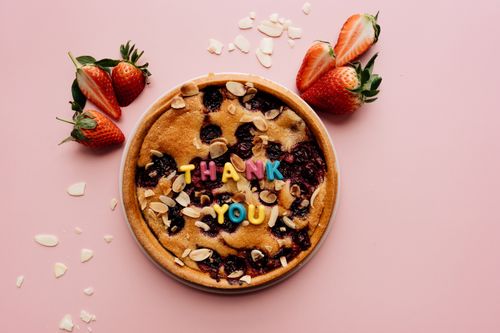 Free A berry pie with colorful 'Thank You' letters and strawberries on a pink surface. Stock Photo