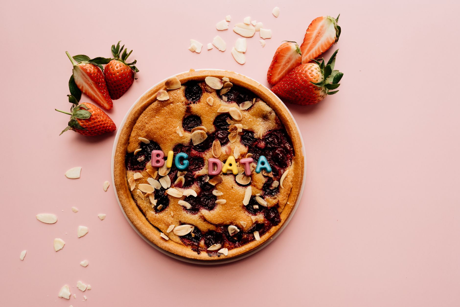 Délicieuse tarte aux fraises avec des tranches d'amande et des lettres colorées 'BIG DATA' sur un fond rose.