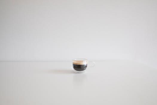 Simple and elegant black coffee in a clear cup on a white surface, ideal for design projects.