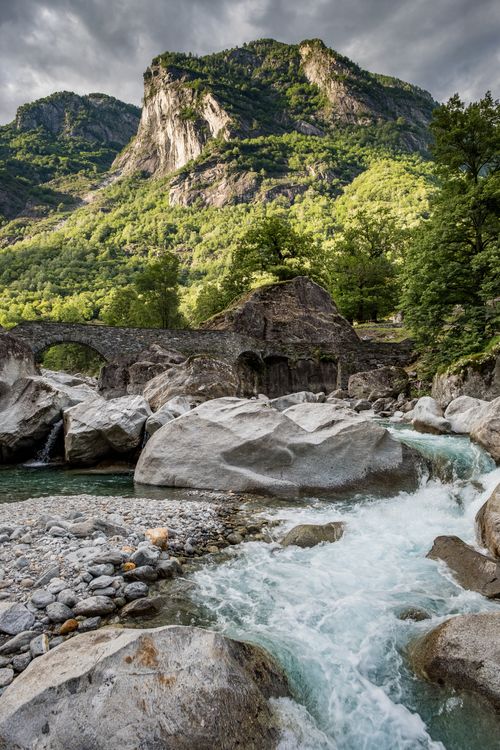 Free Scenic view of a Swiss creek flowing through rocky landscape under a mountainous backdrop. Stock Photo
