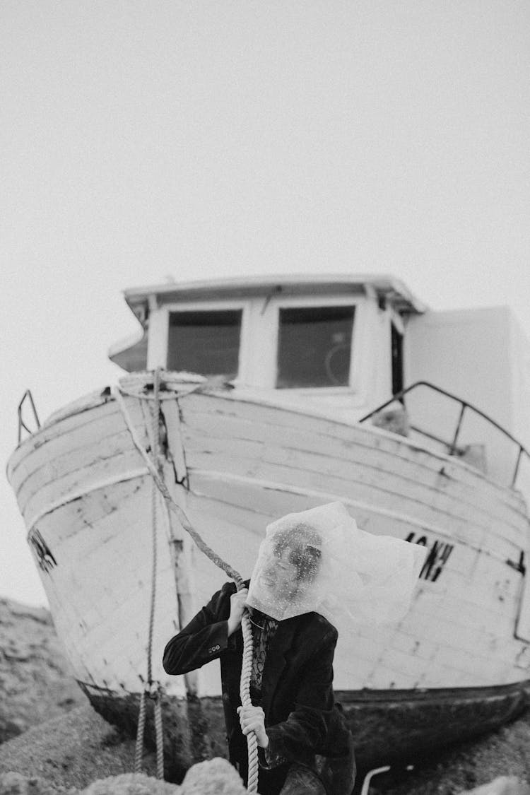 Black And White Photo Of A Woman With Obscured Face Pulling A Boat