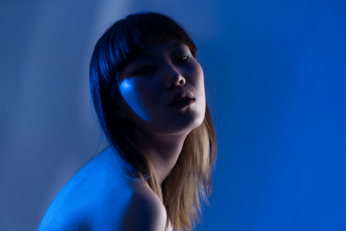 Free Stunning artistic portrait of a woman highlighted by vibrant blue lighting, capturing a moody and dramatic feel. Stock Photo