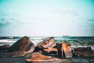 Rough and Polished Rocks on Seaside and Ship on Horizon