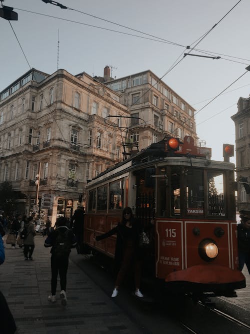 A Red Tram Near a Concrete Building