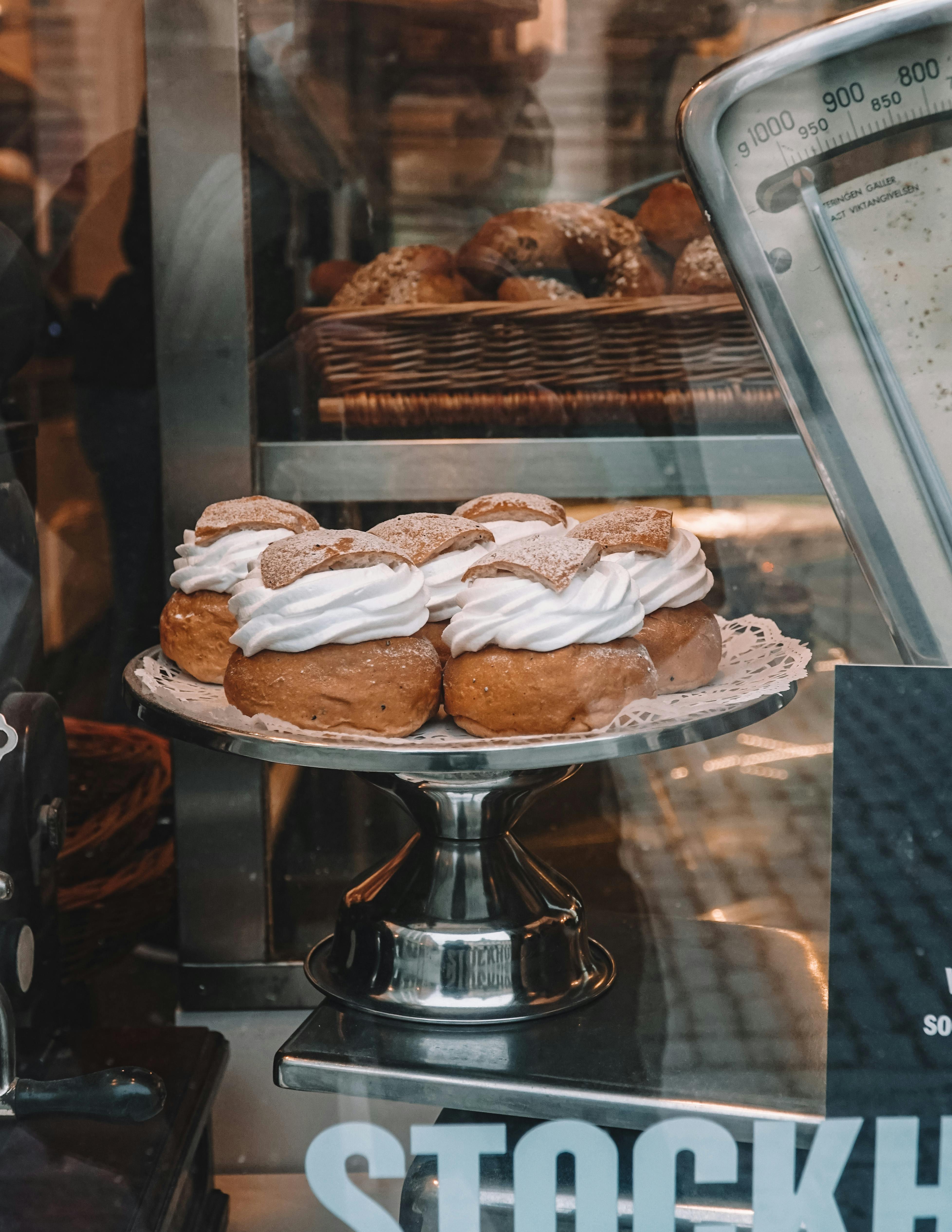 A mouth-watering image of semla pastries topped with whipped cream, displayed in a bakery.