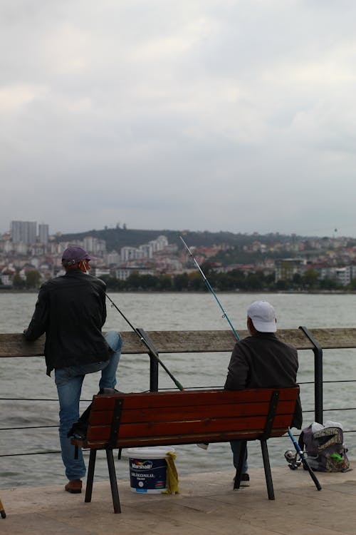 Fishermen with Fishing Rods by River in City