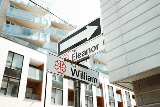 Street signs for Rue Eleanor and Rue William against a modern building in Montreal, Canada.