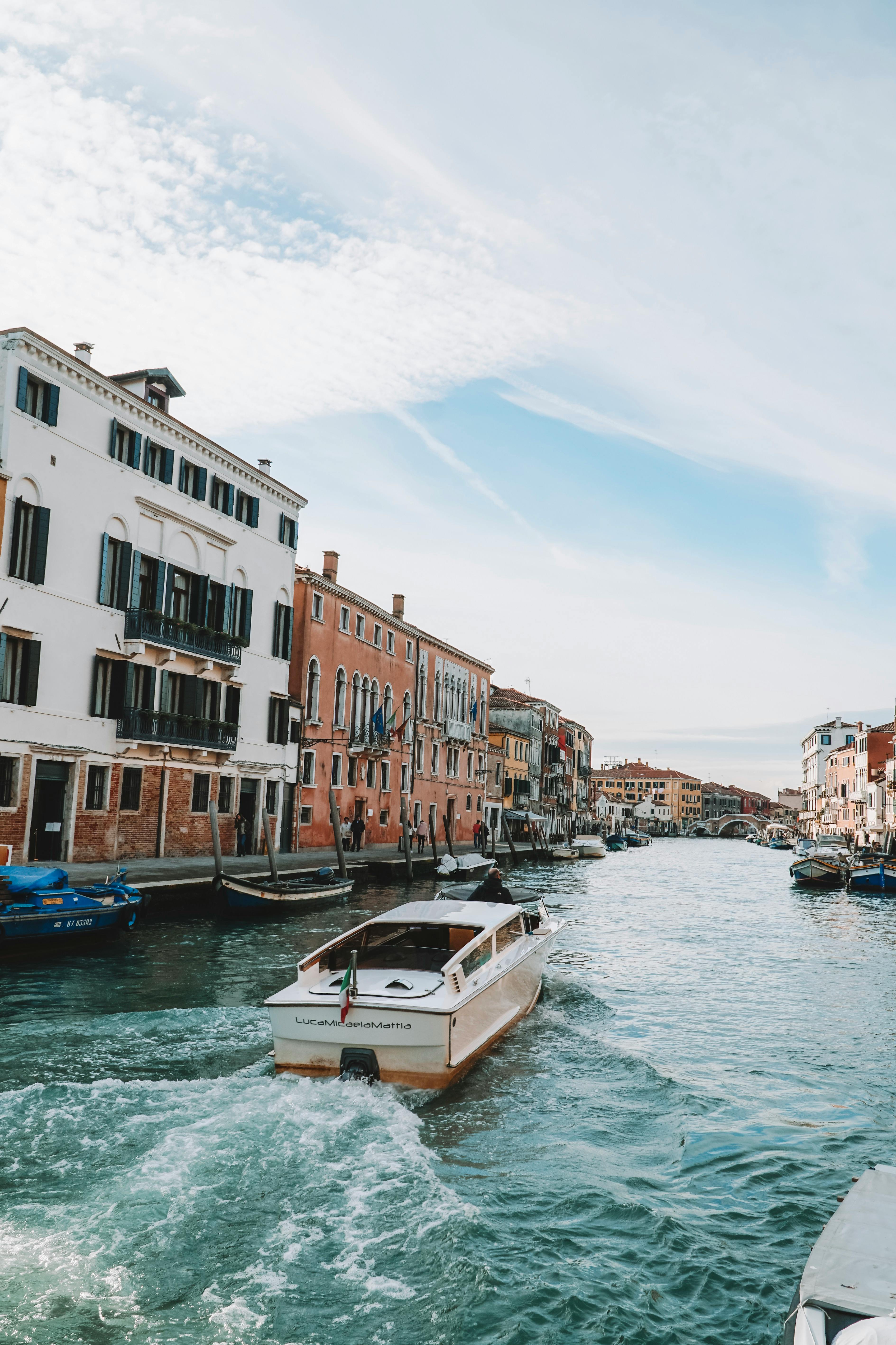Free Explore a picturesque canal in Venice with traditional watercraft and historic architecture in vibrant colors. Stock Photo