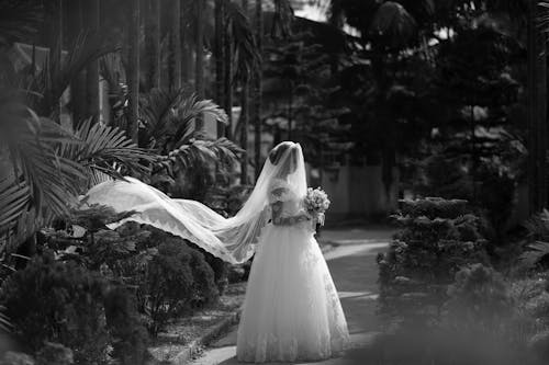 Grayscale Photo of a Bride Holding a Bridal Bouquet