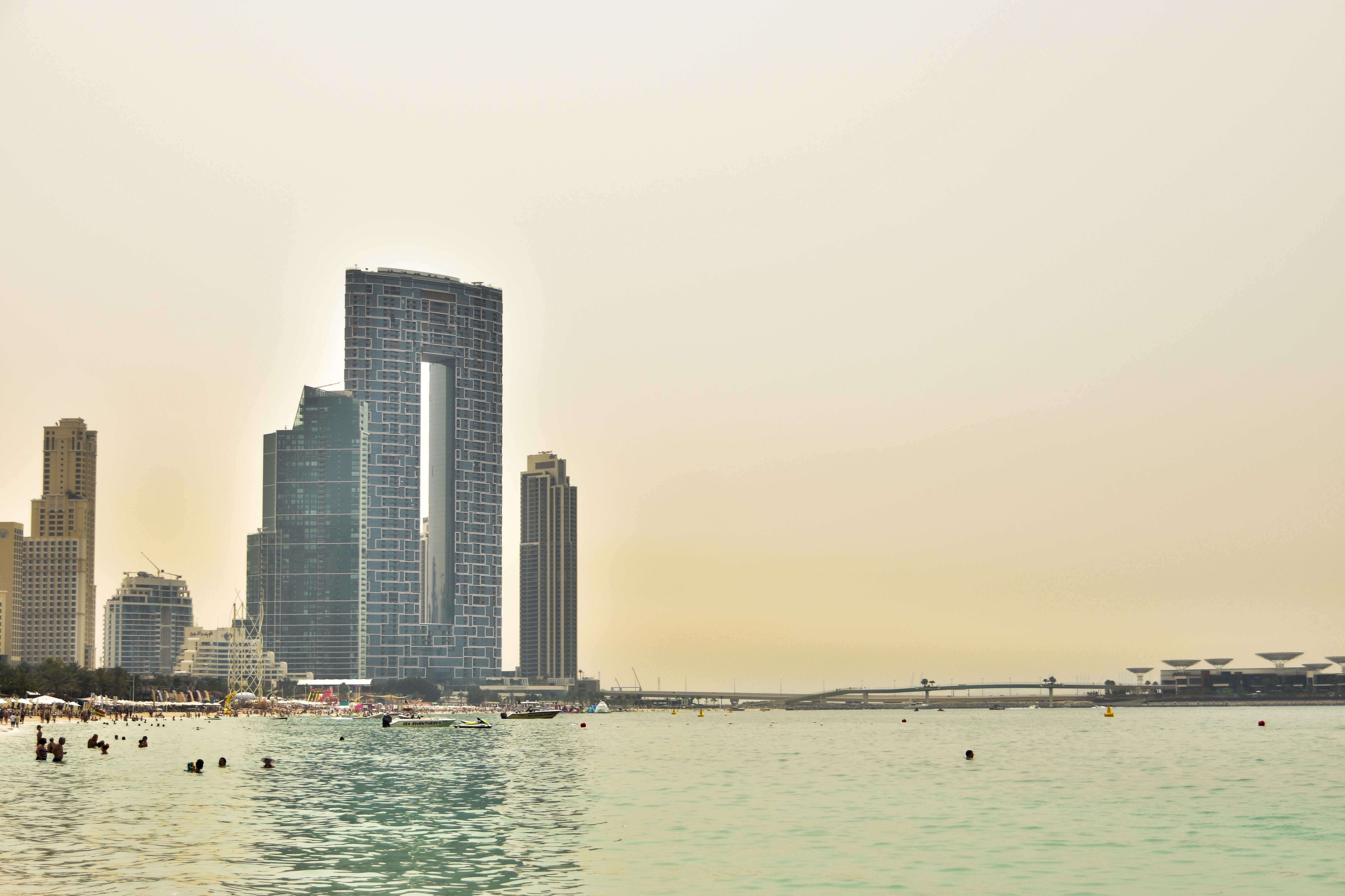 View of Dubai's modern skyscrapers along the coast under a pale sky.