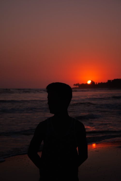 Silhouette of a Person Standing on the Beach during Sunset