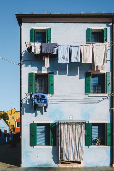 Vibrant laundry drying on a colorful house facade in Venice, Italy.