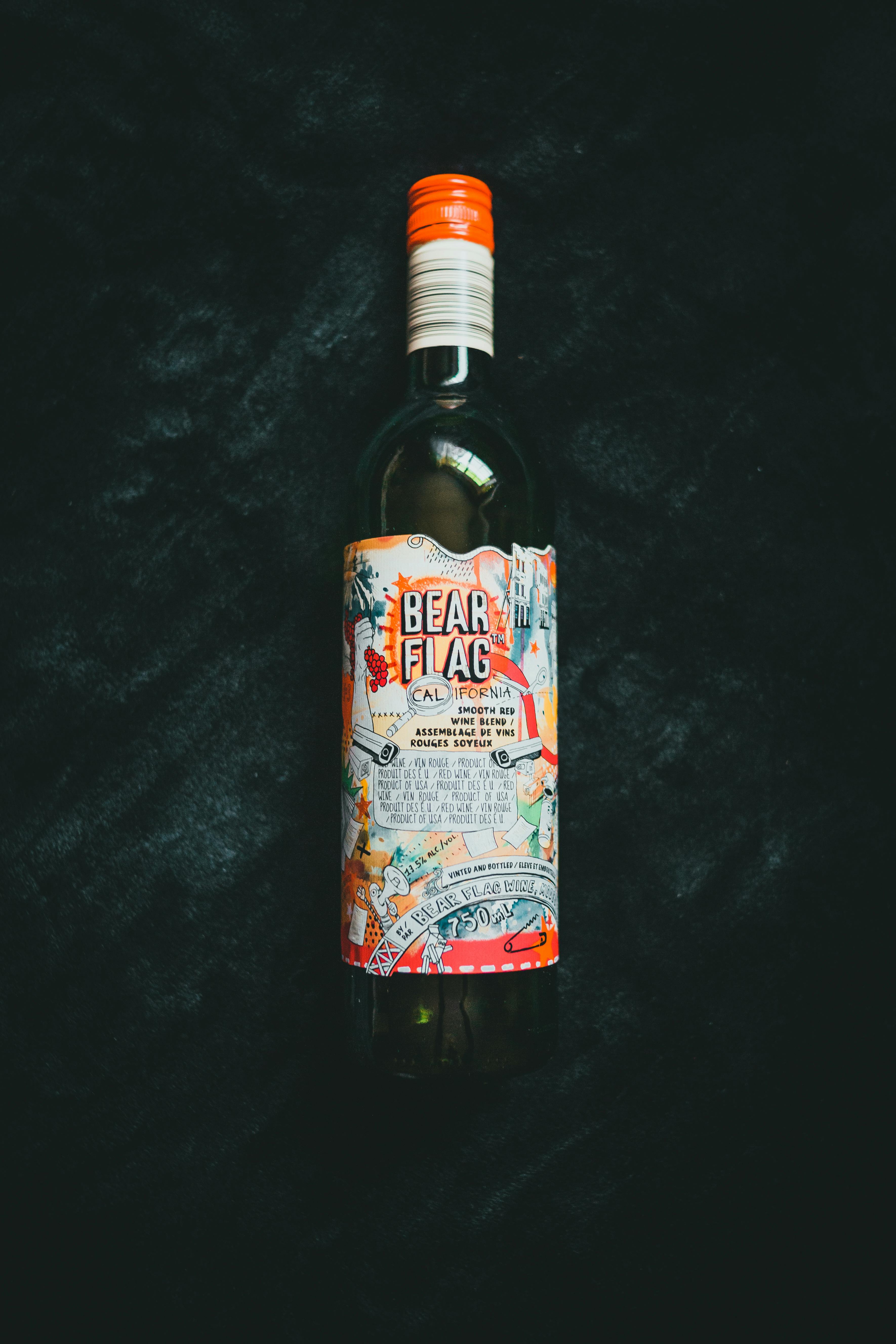 A close-up of a Bear Flag wine bottle with elaborate label against a dark textured backdrop.