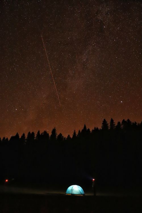 Free A glowing tent under a breathtaking starry night sky, ideal for adventure seekers. Stock Photo