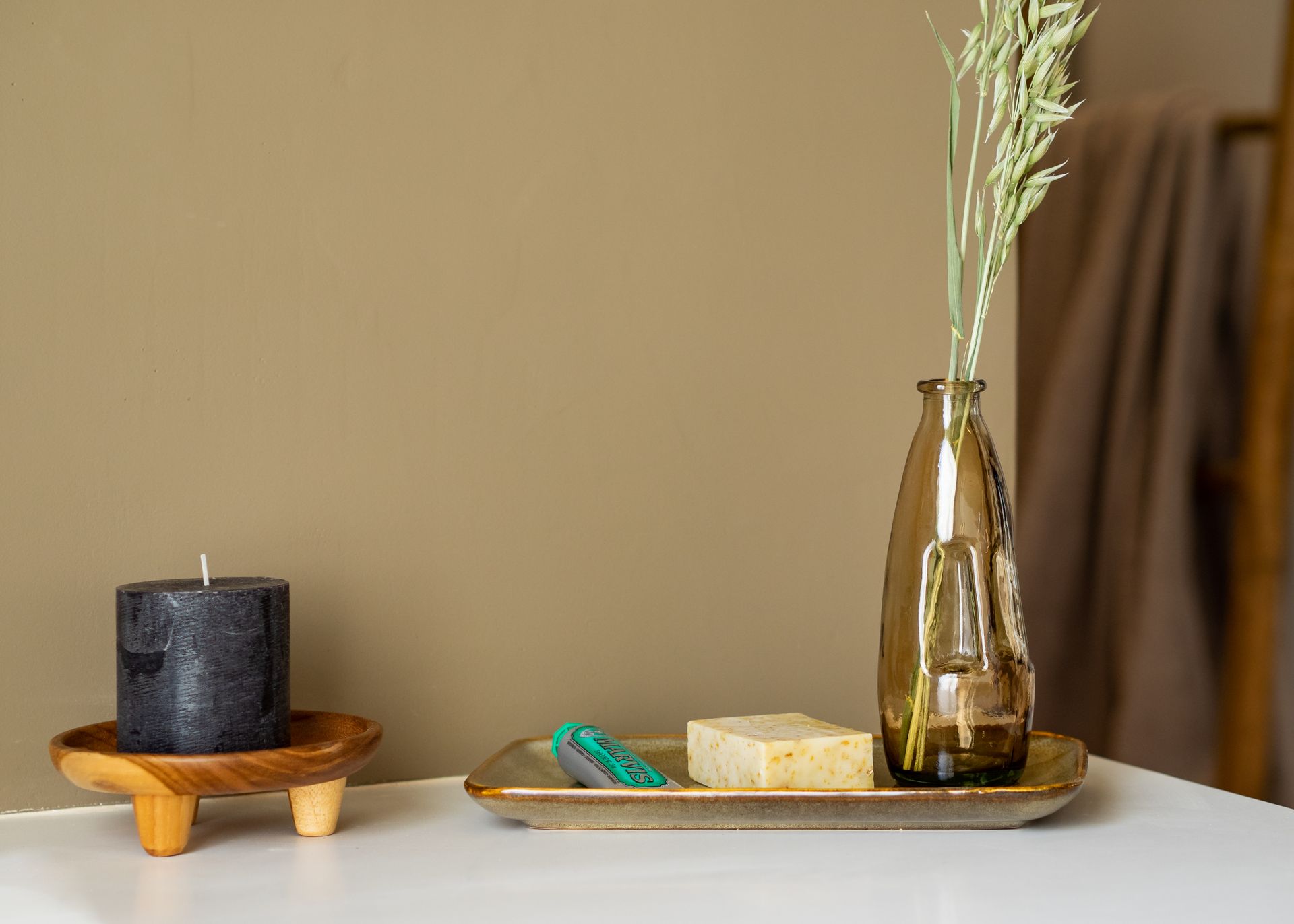 Elegant setup of a glass vase, black candle, and soap on a minimalist table setting.