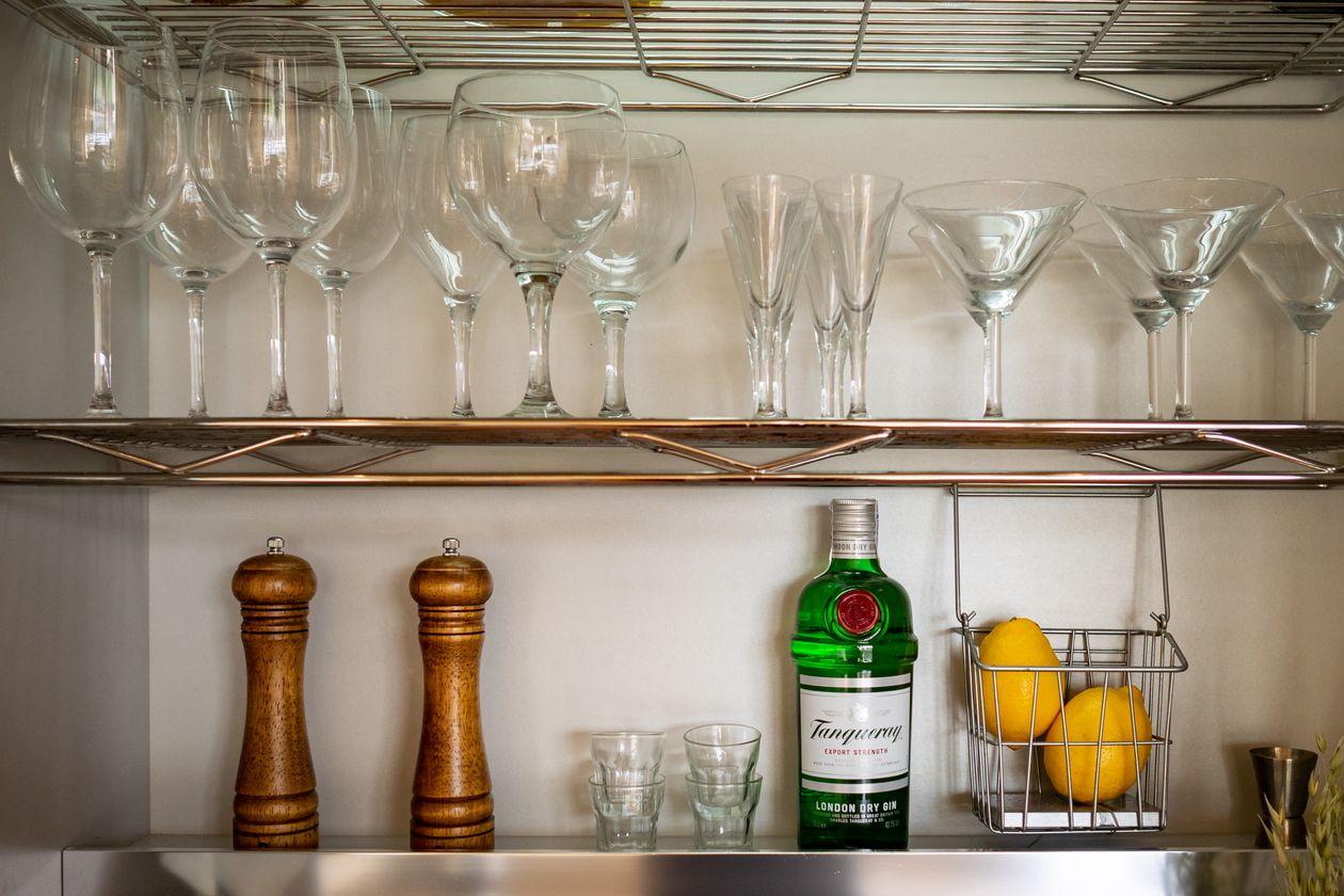 wire shelves styled as a home bar with glasses and bottles